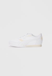 White athletic shoe with a sleek design, synthetic upper, textured rubber sole, and subtle yellow accents on the side and heel.