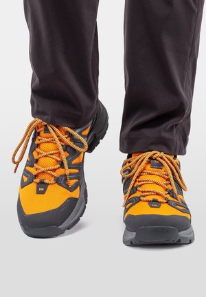 Pomarańczowe i szare buty outdoorowe z siateczkową cholewką, grubymi czarnymi gumowymi podeszwami i kontrastującymi pomarańczowymi sznurówkami. Zaprojektowane z myślą o trwałości i przyczepności.