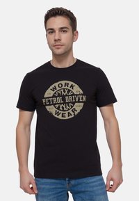Czarny bawełniany t-shirt z wyraźnym beżowym nadrukiem graficznym z napisem "WORK PETROL DRIVEN WEAR" na środku, okrągły kształt z postarzanym detalem.