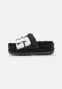 Czarne klapki z puszystym, teksturowanym paskiem oraz wielowarstwową platformą z białym akcentem i wytrzymałą podeszwą.