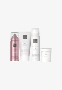 Ensemble de quatre produits de bain : mousse lotion pour le corps rose, crème pour le corps blanche, gel douche moussant blanc et une bougie blanche, tous avec des détails floraux.