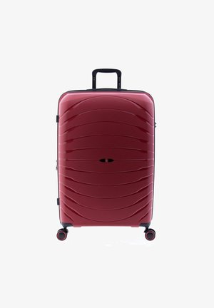 Valise rigide rouge avec une finition brillante, motif en vague, zips noirs, poignée latérale et quatre roues pivotantes à 360 degrés.
