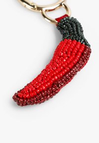 Llavero en forma de chile con abalorios rojos y negros, herrajes dorados brillantes y superficie texturizada, que muestra una artesanía detallada y colores vibrantes.