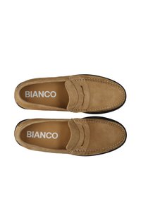 Hellbraune Wildleder-Loafers im Mokassin-Stil, mit genähten Details, runder Zehe und einer schwarzen Gummisohle, die innen mit "BIANCO" beschriftet sind.