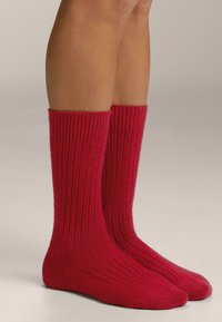 Rode kniekousen van geribbelde stof, met een gestructureerd ontwerp en gladde teennaden voor comfort.