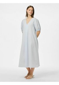 Ljusblå midi-klänning med V-ringning, puffärmar, texturerad tyg och avslappnad passform; bärs med enkla vita flip-flops.