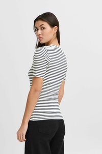 Camiseta de manga corta a rayas en crema y azul marino. Diseño ajustado con cuello redondo y tejido suave. La vista posterior muestra una silueta suave.
