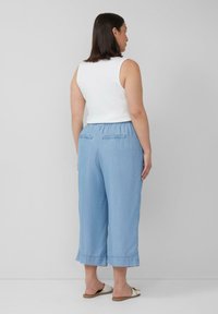 Pantalons culotte en chambray bleu clair avec taille élastique, poches latérales et longueur crop, associés à un haut sans manches blanc.