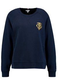 Mörkblå sweatshirt med rund hals och raglanärmar, med en gyllene logotyp på bröstet. Tillverkad av en strukturerad bomullsblandning.