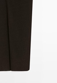 Jupe en tissu marron foncé avec des lignes de couture discrètes, présentée sur un fond blanc uni.