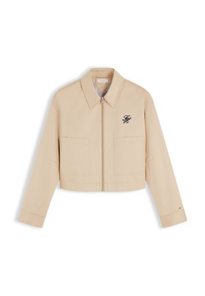 Beige cropped lynlåsjakke med bred krave, to forlommer og lille broderet marineblåt logo på venstre bryst.