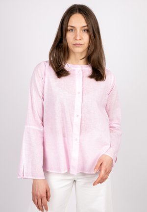 Light pink long-sleeve blouse with a round neckline, chest buttons, and side slits. Made from a textured, lightweight fabric.