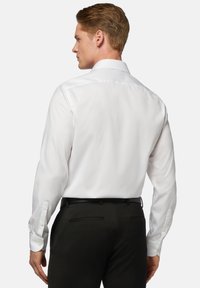 Witte langesleeve shirt met een gladde afwerking, voorzien van een klassieke kraag en knopenmanchetten, gecombineerd met zwarte aansluitende broeken.