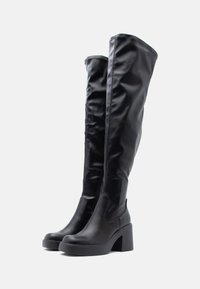 Černé kožené boty po kolena s hladkým, jemným povrchem, blokovým podpatkem a vysokými svršky se jednoduchým prošíváním na okrajích.