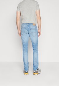 Jeans aderenti azzurro chiaro a vita media, dotati di due tasche posteriori, patch in pelle del marchio e una texture leggermente scolorita.