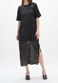 Svart knälång klänning med en avslappnad passform. Tillverkad av strukturerat material som har ett skimrande mönster och sidokilar. Korta ärmar.