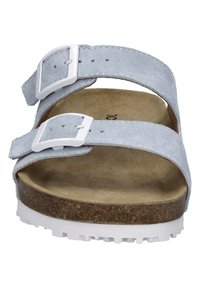 Blauwe suède sandalen met twee verstelbare banden met witte gespen, een natuurlijke kurken voetbed en een gestructureerde witte rubberen zool.