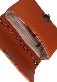 Interno di una borsa in pelle arancione con dettagli in catena, tasca con cerniera e fodera beige. Hardware in metallo e etichetta visibile vicino alla base.