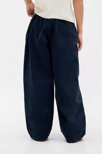 Calças de perna larga azul-marinho com um corte descontraído, apresentando um cinto básico e sem bolsos visíveis ou detalhes de ferragens. Textura do tecido lisa.