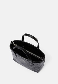 Bolsa tote preta acolchoada com uma superfície texturizada, alças duplas e um compartimento com zíper no interior. Acessórios em prata em destaque.