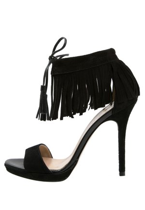 Schwarze, hochhackige Sandale mit einem weichen Wildleder-Obermaterial, Fransen am Knöchel, offener Zehenpartie und einem glänzenden Absatz. Verfügt über einen Schnürverschluss.