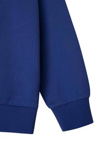 Felpa color blu navy con polsini a coste; superficie liscia; presenta una vestibilità comoda; design minimalista senza motivi o loghi.