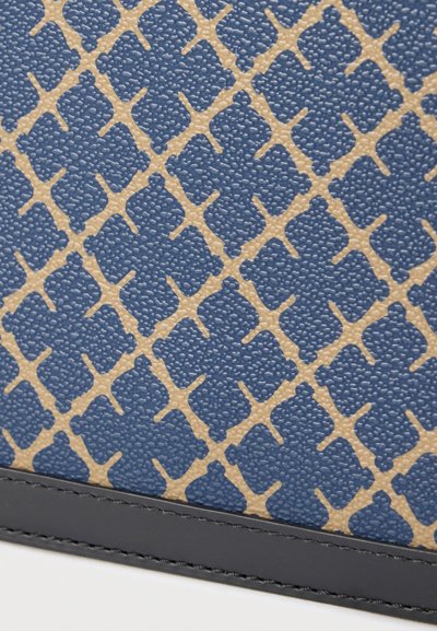 Μπλε υλικό με υφή που διαθέτει ένα γεωμετρικό μπεζ σχέδιο, περιτριγυρισμένο από μια μαύρη δερμάτινη λεπτομέρεια κατά μήκος του κάτω άκρου.