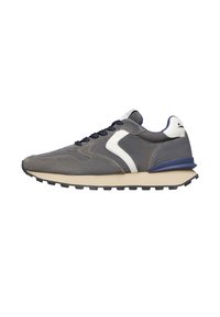 Scarpa atletica grigia con tomaia in suede, dettagli bianchi e lacci blu navy. Presenta una suola intermedia spessa di colore crema e una suola esterna nera testurizzata.