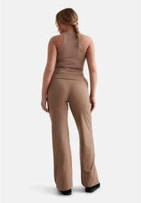 Brown, fitted tank top paired with matching flared pants. Both are made of soft fabric, featuring a smooth texture and minimal seams.