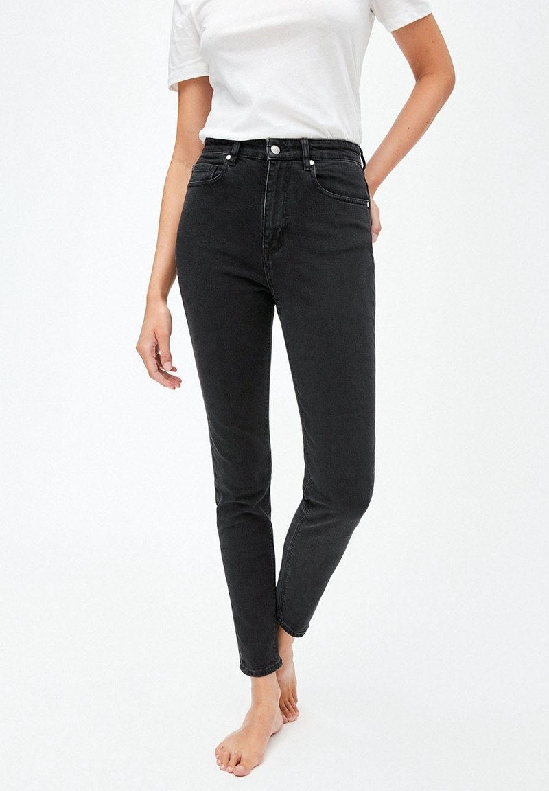 Jean noir taille haute avec une coupe slim. Tissu en denim avec une texture subtile. Comprend une fermeture à boutons à l'avant et un design classique à cinq poches.