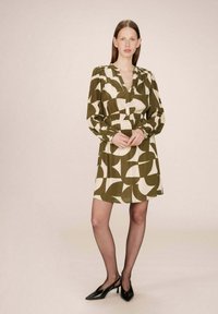Robe à manches courtes avec un motif géométrique vert olive et crème, dotée d'un devant boutonné et d'une taille élastique pour une silhouette ajustée.