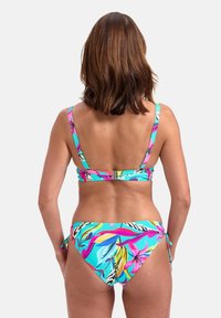 Bikini souprava s tropickým květinovým vzorem v živých barvách na světle modrém pozadí. Nastavitelné svázání na spodní části a sponka na zadní straně.