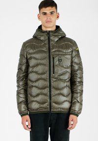 Olivgrüne, gesteppte Pufferjacke mit Kapuze, Frontreißverschluss und Brusttasche; verfügt über einen schwarzen Reißverschluss und gelbe Akzente.