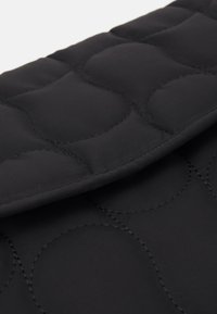 Clutch in tessuto nero trapuntato con una texture liscia e un motivo di cuciture circolari. Presenta una chiusura a patta nella parte superiore.
