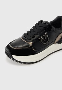 Μαύρο αθλητικό παπούτσι με συν δυασμό λείου δέρματος πατινέ και υφασμένο σουέτ. Στρογγυλερή μύτη, χοντρή λευκή μεσαία σόλα και εξωτερική σόλα από καουτσούκ με σχέδια.