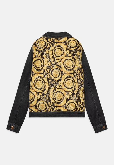 Chaqueta de mezclilla con una base negra y un patrón floral dorado en la parte posterior, y mangas negras sólidas; incluye detalles de botones en los puños.