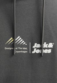 Szara bluza z kapturem ze sznurkiem. Zawiera nadrukowany tekst logo "Jack & Jones" oraz detale wzornicze w białym i żółtym kolorze. Materiał ma miękką fakturę.