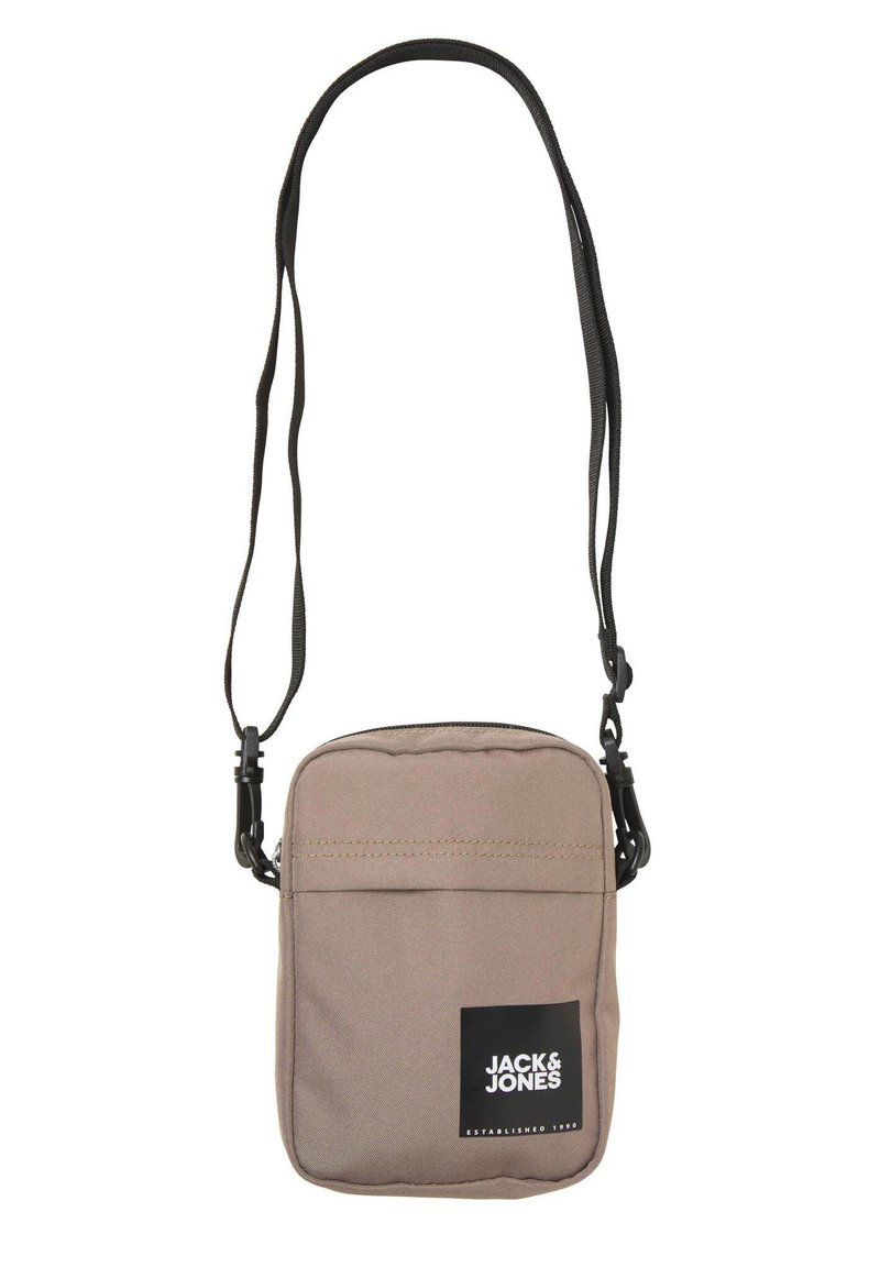 Sac bandoulière en tissu marron avec un compartiment principal zippé, une poche avant et une sangle réglable noire ; présente un patch logo à l'avant.