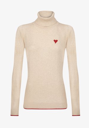 Pull à col roulé beige en matériau doux, avec une petite broderie en forme de cœur rouge sur la poitrine gauche et des accents rouges à l'ourlet.
