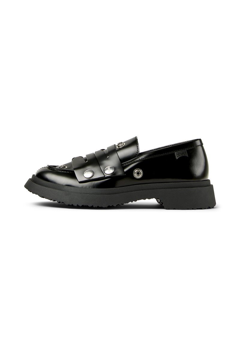 Svarta blanka loafers med en stadig sula, prydda med dekorativa remmar och metalliska detaljer, visade mot en vit bakgrund.