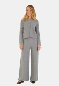 Traje de dos piezas en gris a cuadros con chaqueta corta y pantalones de pierna ancha; cuenta con detalles de botones y una tela texturizada.