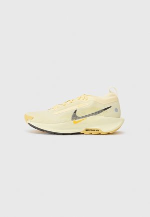 Jasnożółty but do biegania z czarnym i żółtym logo Nike, teksturowaną podeszwą oraz napisem „NIKE TRAIL ATG” na białym tle.