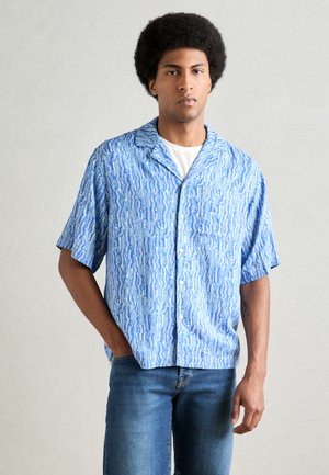 Short-sleeve, button-up shirt in light blue with wavy white and dark blue patterns. Made of lightweight fabric, features a collar and pocket.