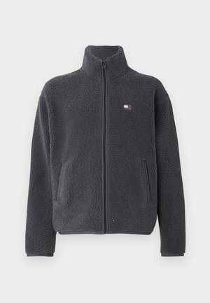 Giacca in fleece grigia scura con colletto alto, zip completa, maniche lunghe e due tasche frontali. Texture morbida con delicato dettaglio del logo sul petto.