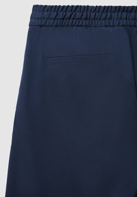 Rückansicht von navyblauen Hosen mit elastischem Bund und einer einzelnen horizontalen Eingrifftasche auf der rechten Seite.