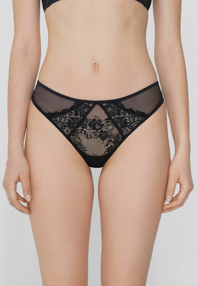 Culottes de bikini en dentelle noire avec des panneaux en maille transparente, des motifs floraux et une coupe taille basse avec une ceinture et des finitions lisses.