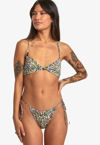 Floral bikini set in black with colorful flowers. Top features a knotted front design; bottom has adjustable side ties. Smooth fabric texture.
