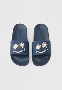 Tamsiai mėlynos gumos šlepetės su tekstūruotu paviršiumi, dirželyje pavaizduotas šviesios spalvos palmės medis ir šypsena. Matomas prekės ženklo logotipas.