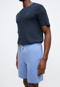 T-shirt azul-marinho de manga curta com nervuras e gola redonda; calções azul-claro com cordão e detalhe de logótipo bordado na bainha.