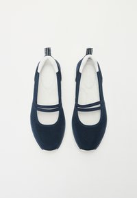 Navy modré slip-on boty s texturovanou tkaninou, bílými podrážkami a dvěma diagonálními pásky přes vrch. Lehké provedení pro příležitostné nošení.